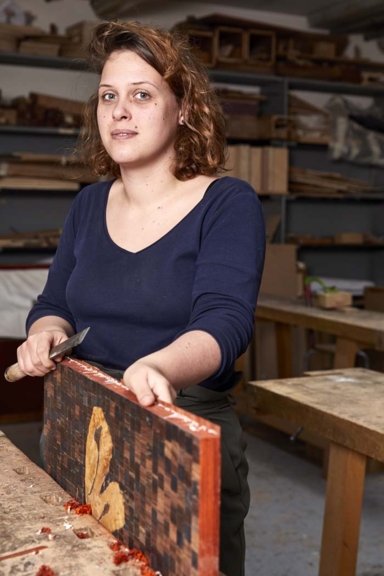 Alice gratte le bois du bord d'un tableau à l'aide d'une spatule